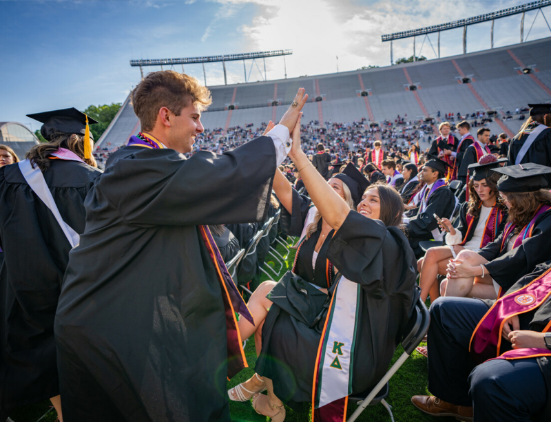 Graduates high five in Lane Stadium