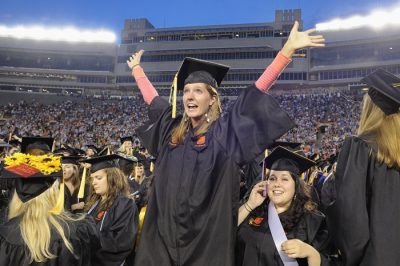 A happy graduate stands among the crowd at the University Commencement Ceremony